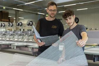 Hightech aus dem Vogtland: Die Fäden von Embro heizen sogar Windräder - Die Firma Embro in Falkenstein ist auf die Entwicklung und Fertigung von technischen und smarten Textilien spezialisiert. Der Stellvertretende Produktionsleiter Sebastian Jäger und Mitarbeiter Dennis Schneider begutachten das bestickte Produkt.