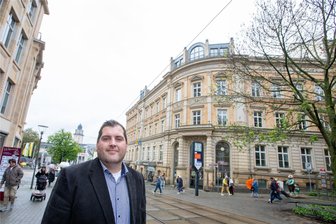 Historisches Gebäude in der Plauener Innenstadt vor spannender Zukunft: Aus der Alten Post soll ein Ärztehaus mit Ladenzeile werden - Joscha Heinen ist Kaufmännischer Leiter des Familienunternehmens Grünter- Immobilien, welches die Alte Post (im Hintergrund) in ein modernes Ärztehaus umwandeln will.