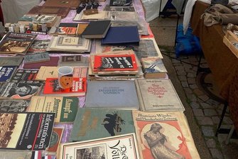 Hitlertasse und fragwürdige Schriften: Zwickauer Grünen-Stadtrat kritisiert Stadtfest-Buden - Feilgebotene Ware an einem Stand auf dem Stadtfest, dazu gehört auch eine Tasse mit stilisiertem Hitler-Gesicht.