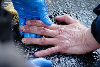 Hitzige Klima-Diskussionen auf der Leipziger Buchmesse: Wie weit darf der Aktivismus gehen? - Ein Polizist löst mit Öl die Hand eines Klimaaktivisten, der sich am Asphalt einer Straße festgeklebt hat: Derartige Proteste führen derzeit zu viel Kontroverse.
