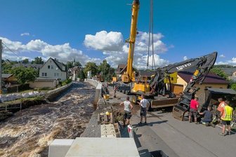 Hochwasserschutz und Feuerwehr in Pockau-Lengefeld: AfD-Stadtrat sorgt für Fauxpas - Am Mittwoch wurde der Bagger, der am Vortag von Fluten der Schwarzen Pockau ins Flussbett gerissen worden war, mit Hilfe eines Krans geborgen. Nach der Demontage des Greifers wurde das Baugerät mit einem Tieflader abtransportiert. An der Stelle lässt die Landestalsperrenverwaltung aktuell Hochwasserschutzwände bauen.