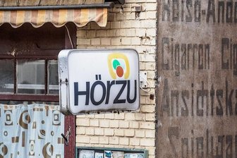 "Hör zu": Als die erste Familien-Illustrierte nach 1945 auf den Markt kam - Die Programmzeitschrift "Hörzu" - hier eine Werbetafel an einem längst geschlossenen Laden - hat über75 Jahre viele Zeiten überlebt.