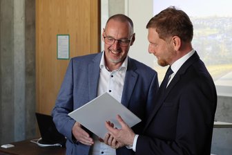 Hohe Würdigung für ein Dorf im Erzgebirge: Breitenbrunn offiziell erster „Hochschulort“ in Sachsen - Bürgermeister Lars Dsaak (l.) erhält von Ministerpräsident Michael Kretschmer die Urkunde.