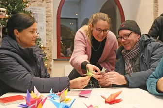 Holocaustgedenken in Zwickau: „Denn nur so gibt es ein ‚Nie wieder‘“ - Sandy (l.) und Heiko Reinhold (r.) basteln unter Anleitung von Anne Sandmann Kraniche gegen das Vergessen.