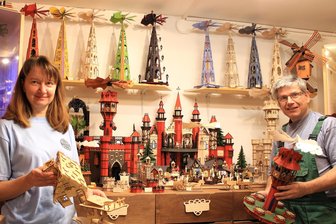 Holzkunstmacher aus Neuhausen entwickeln Marktplatz mit Schwibbogen zum Selbstbauen - Daniela und Matthias Suchfort präsentieren zwei ihrer Modelle. Im Hintergrund der Marktplatz mit Schwibbogen - eine Kreation zum 20. Geburtstag.