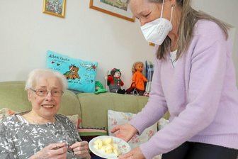 Hospizdienst hat keine Coronapause - Maria Schönfeld ist krank und wird vom Hospizdienst der Diakonie in Freiberg begleitet. An guten Tagen strickt Maria Schönfeld gern. Im Bild: Koordinatorin Barbara Beger (r.) reicht ihr das Mittagessen.
