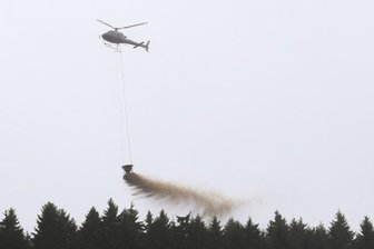 Hubschrauber werfen Kalk über Waldgebiet ab - 