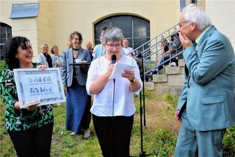 Hühner, Weinreben, ein Baum, Bücher und die Einladung zum Predigen: Reichenbachs Pfarrer Andreas Alders sieht einem unruhigen Ruhestand entgegen - Noch gibt es die Hühner, ein Geschenk der Mitarbeiter, nur auf dem Papier. Demnächst ziehen sie bei Andreas Alders ein. Kantorin Sarah Stamboltsyan und Pfarrerin Ulrike Penz übergeben das Geschenk der Mitarbeiter.