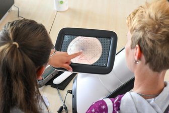 „Ich habe keinen Augenarzt-Termin bekommen“: Großes Interesse an privatem Sehtest-Angebot in Hartmannsdorf - Mirantus-Mitarbeiterin Maxi Paula Morgenstern wertet mit einer Patientin Fotos von der Netzhaut eines Auges aus.