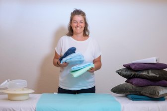 „Ich lehre Angehörige, wie sie richtig und leichter pflegen“ - Praktisches für die Pflege daheim: Marlen Mirschel zeigt Inkontinenzmaterial, links eine Bettpfanne und eine Urinflasche für Frauen, rechts Lagerungskissen und einen Lagerungskeil in Weiß.