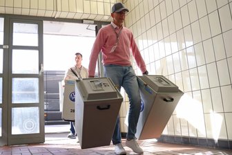 IG Metall bleibt stärkste Kraft: Betriebsratswahl im VW-Werk Zwickau entschieden - Im VW-Stammwerk Wolfsburg tragen Mitarbeiter versiegelte Wahlurnen an den Auszählort. Die Behälter mit den Stimmzetteln im Zwickauer VW-Werk sehen ähnlich aus.