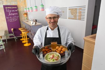 Ihre Zukunft ist kross und rund: Ukrainer starten mit frittierten Bällchen in Chemnitz neu durch - Dmytro Volkov mit Käse- und Fleischbällchen, die er selbst entwickelt hat.