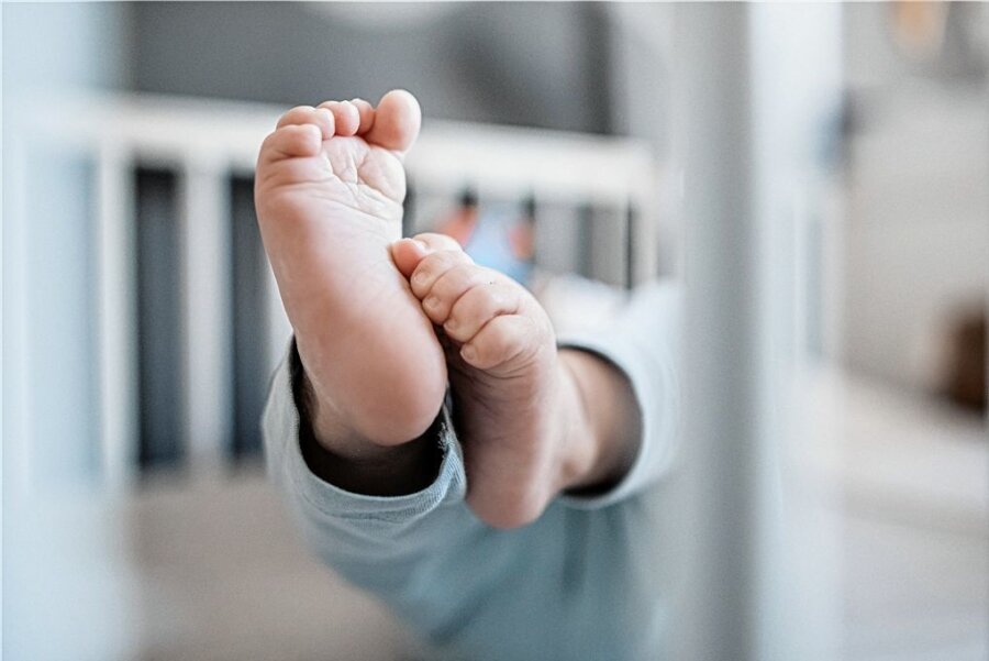 Im Erzgebirge kamen 2022 mehr als 1600 Babys zur Welt - Füße eines Babys im Kinderbett: Im Erzgebirgskreis kamen 2022 ähnlich viele Kinder wie im Vorjahr zur Welt. 