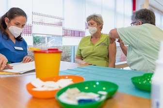 Impfteam der Johanniter bittet in Auerbach das Pflegepersonal zur Nadel - Johanniter impfen im Auerbacher Seniorenheim Panoramablick gegen Corona. Eine Impfung erhalten dort Patienten, Pflegekräfte, Mitarbeiter und deren Angehörigen. Im Bild erhält Martina Zschuch von Schwester Andrea eine Impfung. Dr. Tabea Moormann nimmt die Dokumentation vor.