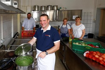 In der Hohenstein-Ernstthaler „Löffelstube“ gibt es endlich wieder warmes Essen - Bertram Blümel (vorn) und Lars Kluge schauten am Dienstag in der Küche der „Löffelstube“ vorbei. Hinten im Bild: Birgit Riedel und Grit Freygang.