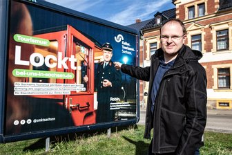 In Eisenbahnuniform auf Werbetour in der Region: Wie ein Markersdorfer Sachsen als Reiseland attraktiver macht - Mit dem Slogan „Tourismus lockt" ist Robin Helmert in den nächsten Wochen auf solchen Großplakaten des Sächsischen Kultusministeriums in der Region zu sehen.