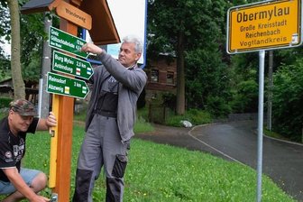 In Reichenbach werden die Wanderwege auf Vordermann gebracht - Ulrich Sörgel (stehend) und Michael Reumann beim Aufstellen des nagelneuen Wanderwegweisers an der Ecke Hauptstraße/Friesener Weg im Reichenbacher Ortsteil Friesen. 