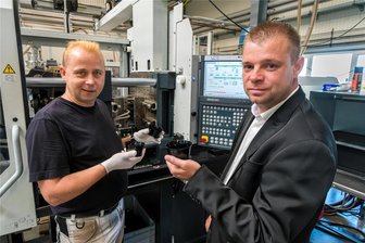 Insolvenz von Aluchrom: Mitarbeiter des Automobilzulieferers aus dem Erzgebirge haben Grund zur Hoffnung - Geschäftsführer Sascha Spartmann und Mitarbeiter Ronny Morgenstern (v. r.) besprechen an einer Spritzgussmaschine die Produktion von Reflektorrohlingen.