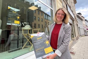 Interaktive Reihe „Gib deinen Senf* dazu“ startet in Reichenbach - Annegret Thalwitzer vor ihrem Büro mit dem Plakat für die interaktive musikalisch-literarische Reihe „Gib deinen Senf* dazu“, die am Montagabend startet.
