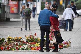 Internationale Pressestimmen zu Chemnitz - Passanten stehen am Tatort an der Brückenstraße, an dem zahlreiche Blumen und Kerzen niedergelegt wurden.