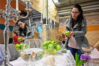 Iranisches Neujahrsfest in Chemnitz: 13 Tage voller Bräuche und Freude - Getrübt von der Protestwelle in der Heimat - Massumeh Banbertina an einem Tisch, auf dem die sieben wichtigen Speisen des Noruz-Festes präsentiert werden. Äpfel stehen für Gesundheit. Der Spiegel steht für Wahrheit und die Fische werden am Ende der Natur zurückgegeben. 