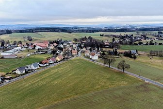 Irfersgrün bekommt Traum-Kita aus Holz - Blick auf das künftige Bauland im Dreieck zwischen Hauptmannsgrüner Straße (links) und der Irfersgrüner Bahnhofstraße. Im Dreieck vorn soll ein neues Feuerwehr-Depot entstehen, rechts im Eck entlang der Bahnhofstraße ist Platz für die  neue Kita samt neuem Spielplatz. 