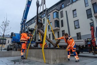 "Jahrhundertschritt" wird fest verankert auf dem Solbrigplatz - Mitarbeiter des Hoch- und Tiefbau Reichenbach, vorn Steffen Holzmüller und Klaus Schädlich (r.), lassen den auf einem Betonquader befestigten "Jahrhundertschritt" in die Fundamentgrube ein.