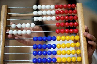 Johanngeorgenstadt macht Weg für Kita-Trägerwechsel frei - Ein Kindergartenkind spielt in einer Kindertagesstätte mit einem Rechenschieber.