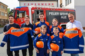 Jugendfeuerwehr im Erzgebirge rüstet auf: Neue Helme, Jacken und Schuhe für Nachwuchsretter - Freuen sich über die neue Schutzkleidung für die Jugendfeuerwehr Aue: Die Jugendwarte René Klotz und Michelle Wächtler (beide l.) mit ihren Schützlingen Felix und Marie Rehm (hinten) sowie Mila Voigt und Sandro Decker (vorn). Ebenfalls mit im Bild: Stadtwerke-Geschäftsführer René Rücker (r.).
