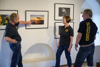 „Kaleidoskop unserer Welt“: Augustusburger Fotofreunde präsentieren sich in der Turmgalerie - Die Mitglieder der Augustusburger Fotofreunde Michael Jahn, Claudia Jahn und Holger Seiler (v. l.) begutachten die Fotos ihrer aktuellen Ausstellung in der Turmgalerie auf Schloss Augustusburg.