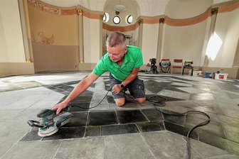 Kapelle in Meerane: Reste von Vergoldungen an Säulen entdeckt - Uwe Ziegler von der Firma Schuhricht aus Remse beim Aufarbeiten des alten Steinfußbodens in der Meeraner Friedhofskapelle.