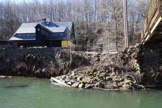 Kehrtwende beim Kauf des Schwarzen Hauses bei Halsbach: Scheitert der Traum vom Dorfzentrum? - Das Schwarze Haus an der Mulde bei Halsbach. Erkennbar sind die Schäden an der Flussmauer.