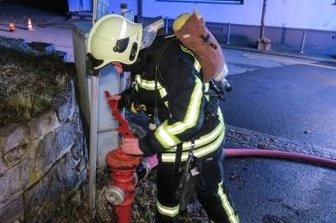 Kellerbrand macht Haus unbewohnbar - Ein Feuerwehrmann schließt den Hydranten an.