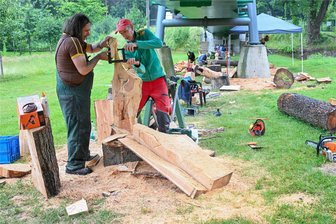 Kettensägenkunst unter der Hängebrücke: Künstler versammeln sich im Chemnitztal - Silvio Ukat (links) und Georg Janthur beim Bearbeiten eines Holzstammes. Janthur sägt aus Esche-Holz verschiedene Kleidungsstücke wie Schuhe, Hose und Weste. Ukat ist bekannt für seine Holz-Tiere wie Raben. Am 30. Juni werden die Skulpturen öffentlich versteigert.