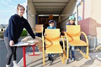 Kinder aus Halsbrücke verpacken Hortmöbel für die Ukraine - zusammen mit der Ukrainerin Arina - Arina Tyvonenko (von links) aus der Ukraine und die Hortkinder Julius und Lenny haben am Mittwochabend vor der Kita "Wirbelwind" in Halsbrücke geholfen, Stühle und Tische auf einen Lkw zu laden. Das Mobiliar soll in eine Schule im Gebiet Charkiw gebracht werden, die im Krieg teilweise zerstört worden ist.