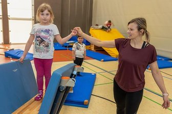 Kinder toben durch Parcours in der Auerbacher Schloss-Arena - Sportmanagerin Claudia Minz führt Milla von der Kindertagesstätte Wirbelwind in Rempesgrün durch den Parcours. 