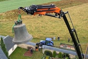 Kirche jetzt vorübergehend ohne Glocken - Die große Glocke wird per Kran auf einen Anhänger außerhalb des Friedhofs gesetzt.