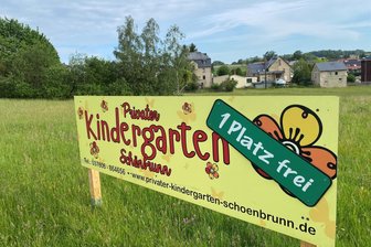 Kitaplatz-Anzeige an der A 72: Warum der Schönbrunner Kindergarten Belegungszahlen auf einer Wiese veröffentlicht - Weit und breit einmalig. Auf einer Wiese an der B 94 hoch zur Autobahn informiert der private Kindergarten Schönbrunn über die Anzahl der aktuell freien Kita-Plätze. Der Kindergarten steht weiter hinten im Dorf - es ist die 1906 erbaute und später länger ungenutzte Dorfschule, in die seit 2016 wieder Kinder gehen.