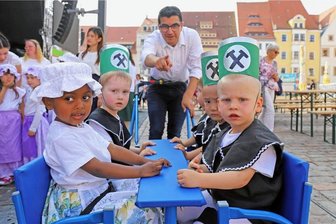 Kleine Aufwartung zum Bergstadtfest in Freiberg: Stadt blickt auf das Wetter - Erzieher Firas Almohamed zeigt den Bergstadtzwergen, wo die Kamera ist.