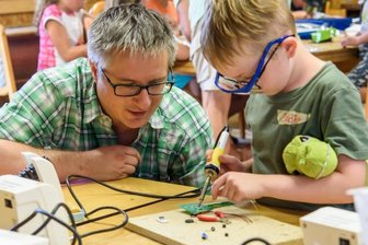 Kleine Technikfans campen in Mittweida - Mit Unterstützung von Hochschulmitarbeiter Falko Jahn lötet Eddie unterm Dach des Müllerhofs einen Morsetaster zusammen. Am ersten Technikcamp in Mittweida nehmen 21 Kinder teil.