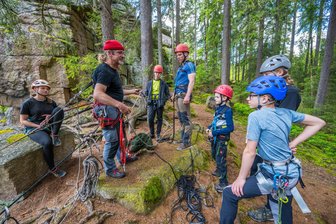 Klettern im Erzgebirge: Warum ein Team für neue Routen in den Felsen das Putzen übt - Michael Scholz (mit der roten Mütze) leitet das Outdoorteam Westerzgebirge. In einem Workshop an den Teufelssteinen bei Johanngeorgenstadt hat er mit Kindern und Jugendlichen das richtige Abseilen geübt.