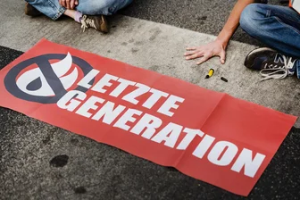 Klimakleber: Was Mitglieder der Letzten Generation in Freiberg machen - Ein Aktivist der Gruppe "Letzte Generation" blockiert eine Kreuzung. Mittlerweile wollen sich die Klimaschützer nicht mehr ankleben.