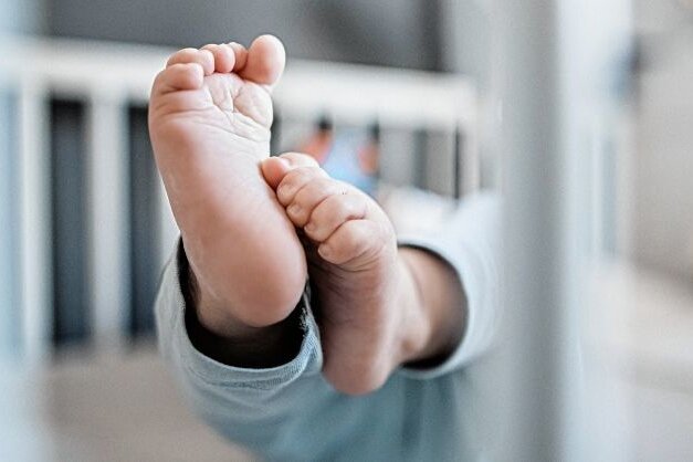 Kliniken im Erzgebirge melden 1653 Geburten - Füße eines Babys im Kinderbett: Im Erzgebirgskreis kamen 2022 ähnlich viele Kinder wie im Vorjahr zur Welt. 