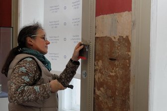 Knifflige Aufgabe auf Schloss Wildenfels: Wie bekommt der Rote Salon seine alte Pracht zurück? - Bevor Restauratorin Henrike Tuchel die Tapetenbahn im Roten Salon abnehmen kann, um sie in ihr Atelier zu schaffen, müssen die Leisten entfernt werden, mit denen die textile Wandbespannung befestigt ist.