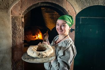Knuspriges Brot und fesselnde Action auf Schloss Rochlitz: Zeitreise ins Hochmittelalter - Natascha Dobos bei der Schlossbelebung in Rochlitz mit einem Kranzbrot, gebacken nach einem Rezept aus dem 15. Jahrhundert.