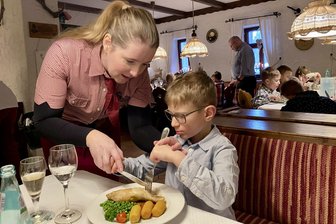 Köhlerhütte im Erzgebirge lädt Vorschüler zum Knigge-Kurs - Gerade sitzen und die Hähnchenkeule nicht in die Hand nehmen! Bedienung Kristin Zacharias zeigt Vorschüler Emil Hecker die richtige Technik des Besteckhaltens beim Hauptgang.