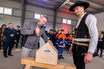 „Können es kaum erwarten“: Für Feuerwehrleute im Erzgebirge beginnt bald ein neues Kapitel - Oberbürgermeister André Heinrich versenkt den symbolischen Nagel, rechts: Zimmerer Ronny Ebert.