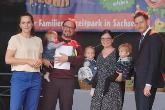 Kretschmer als Patenonkel: Freizeitpark wird zum Drillings-Mekka - Annett Hofmann (l-r), Ehefrau des sächsischen Ministerpräsidenten Kretschmer, Edgar Kapler, Verena Kapler und ihre Drillinge aus Leipzig, sowie Michael Kretschmer, Ministerpräsident des Landes Sachsen, stehen im Freizeitpark Plohn im Vogtland auf einer Bühne. Dort wurden Patenschaften des Ministepräsidenten für neu hinzugekommene Drillinge übergeben.