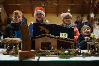 Krippenwettbewerb im Erzgebirge: Projekt aus Hort und Krippe mit Figuren aus Südtirol gewinnen - Vier Kinder der Kita „Spatzennest“ stehen stellvertretend für die rund 60 Grundschüler, die die Krippe gemeinsam gebastelt hatten, hinter ihrer Siegerkrippe.