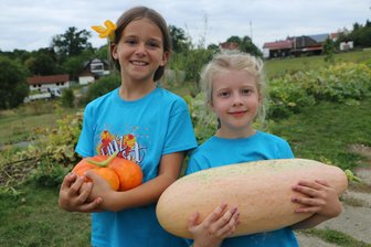 „Kürbisse wachsen nun mal nicht im Juni“: Weischlitz feiert den Herbst mit Kürbissen, Drachen und Musik - Elena und Elena zeigen ihre Kürbisse. Und eine Kürbisblüte im Haar.